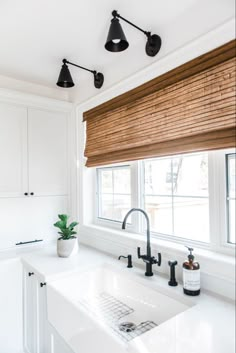 a kitchen sink under a window with wooden shades