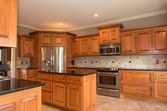 a large kitchen with wooden cabinets and stainless steel appliance, granite counter tops