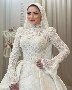 a woman in a white wedding dress with long sleeves and a veil on her head