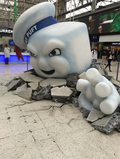 there is a giant statue of a chef in the middle of an airport lobby with people walking around