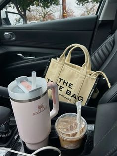 there is a coffee cup, tote bag and other items in the car