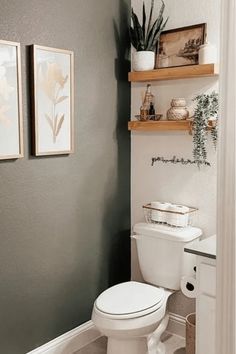 a white toilet sitting in a bathroom next to two pictures on the wall above it