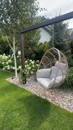 a swing chair in the middle of a garden