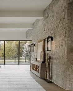 a living room filled with furniture and large windows next to a stone wall covered in glass doors