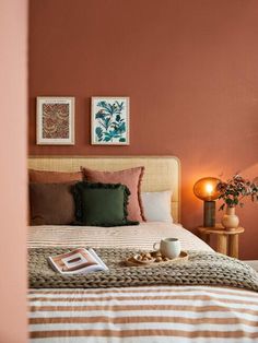 a bedroom with orange walls and striped bedspread, coffee cup on the bed