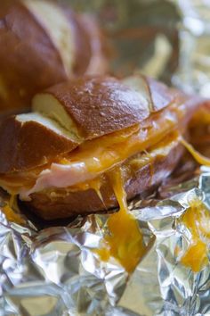 ham and cheese sandwich sitting on top of aluminum foil covered in melted cheese, mustard and ketchup