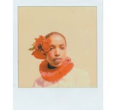 a polaroid photograph of a woman with flowers in her hair and an orange scarf around her neck