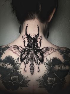 the back of a woman's neck with a beetle tattoo on it