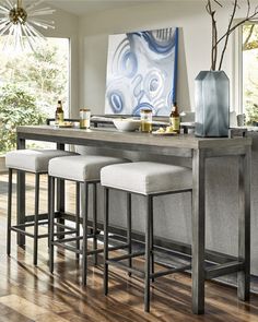 three stools are sitting at the bar in front of a large painting on the wall