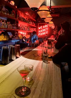 a bar with two glasses on the counter and neon signs above it that read, we are hanky park