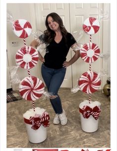 a woman standing next to two buckets filled with candy canes