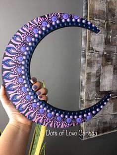 a person holding up a purple and blue circular object with dots of love canada written on it