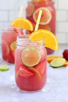 two mason jars filled with watermelon, lemon and limeade drink next to sliced fruit