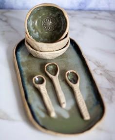 there are three spoons and two bowls on the tray with it's handles