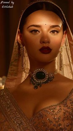 a woman in a wedding dress with a veil on her head and jewelry around her neck