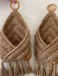 two crocheted baskets with wooden handles and tassels hanging from the sides