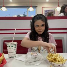 a woman sitting at a table eating french fries