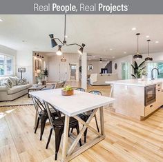 a large open concept kitchen and living room with wood flooring, white walls and ceiling