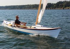 a man riding on the back of a small sailboat