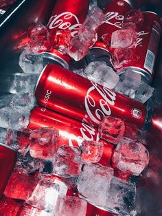 coca - cola cans are stacked on top of ice cubes