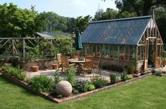 an outdoor garden area with chairs, table and potted plants in the middle of it