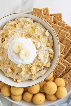 a bowl filled with bananas and cream cheese surrounded by crackers on a white plate