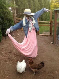 a woman in a pink dress and cowboy hat standing next to two chickens on the ground