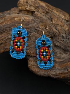 a pair of beaded earrings sitting on top of a piece of drifty wood