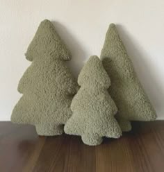 three small green trees sitting on top of a wooden table