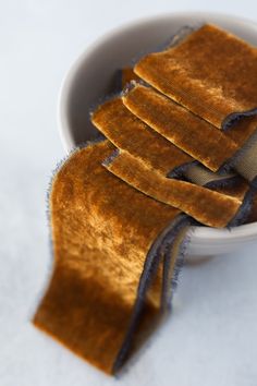 a white bowl filled with lots of brown stuff next to a blue ribbon on top of it