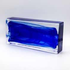 a blue glass block sitting on top of a white table next to a black box