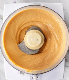 an overhead view of a food processor with peanut butter in it on a marble surface