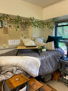 a bed with lots of pillows and blankets on top of it in a room next to a window