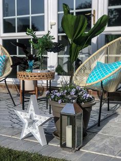 some chairs and tables with plants in them on the ground near a building window sill