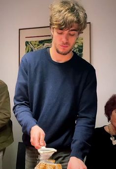 a man standing in front of a cake with frosting on it and toppings