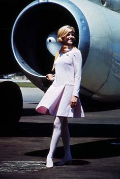 a woman in a white dress is standing next to an airplane's engine compartment