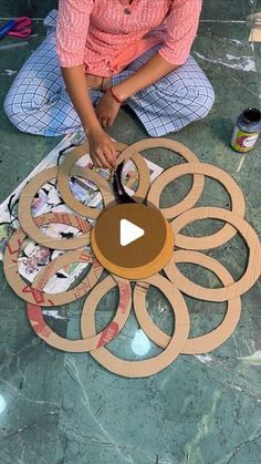 a woman sitting on the floor working on an art project with wood circles and paint