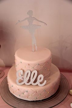 a pink cake with a ballerina on top and the word eef spelled out