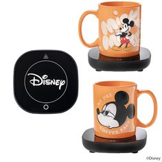 two coffee mugs with mickey mouse designs on them, one is orange and the other is black