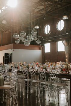 an empty banquet hall with clear chairs and round chandeliers hanging from the ceiling