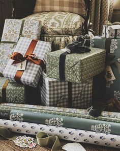 a pile of wrapped presents sitting on top of a floor next to a chair and window