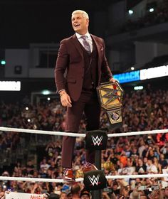 a man in a suit standing on top of a wrestling ring