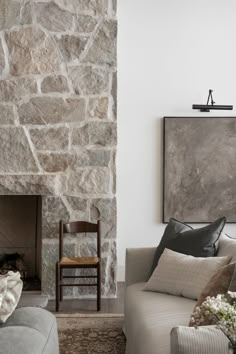 a living room filled with furniture and a fire place in front of a stone wall