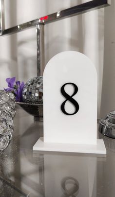 a white and black table with a number 8 on it's base in front of a mirror