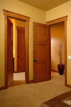 an empty room with three doors and a vase on the floor