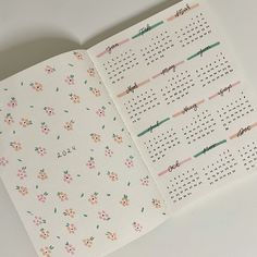 an open calendar book with floral designs on the pages and numbers in pink, green, orange and blue