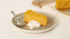 a slice of pumpkin cheesecake with whipped cream on a plate next to a fork