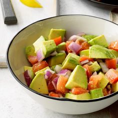 a white bowl filled with sliced up vegetables and avocado on top of a table