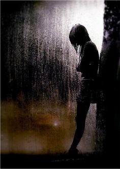 a woman standing in the rain with her head down