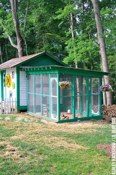 a small green and white shed in the woods